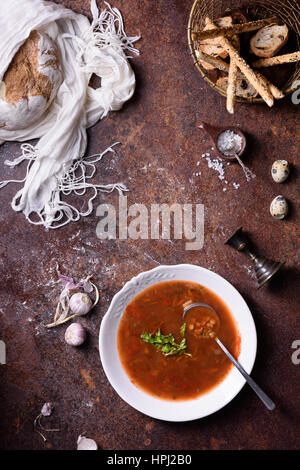 Traditionelle Gemüse Gazpacho Suppe mit Gewürzen und Brot. Rustikaler Hintergrund direkt von oben. Stockfoto