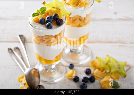 Joghurt-Müsli-Parfait mit Mango und tropischen Früchten, geschichtete Dessert oder Frühstück Stockfoto