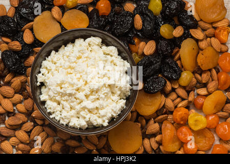 Hüttenkäse in weiße Schale. Pflaumen, getrocknete Aprikosen, getrocknete Mandarinen und Mandeln Nahaufnahme. Stockfoto