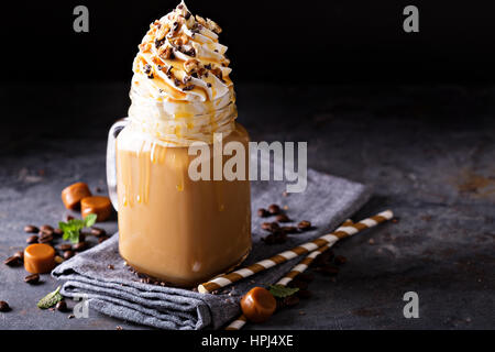 Caramel iced Latte mit Sahne und Sirup auf dunklem Hintergrund Stockfoto