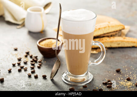 Heißen Kaffee Latte mit braunem Zucker und Biscotti Kekse in Longdrinkglas Stockfoto