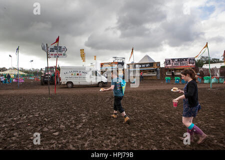 Ricky Pateman und Fe Evans aus Stevenage, die ihren Weg durch den Schlamm mit ihrem Frühstück am Morgen des 3. Tag von Glastonbury Musik Festi Stockfoto