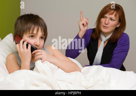 Model Release, Sohn Im Bett Mit Handy, Schimpft Mutter - Sohn mit Handy im Bett, Mutter schimpft Stockfoto