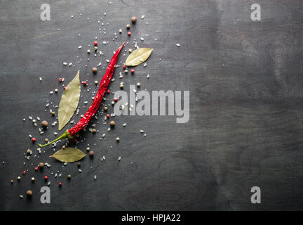 Rote Paprika, scharfe Gewürze und Lorbeerblatt auf dem schwarzen Baum. Ansicht von oben. Platz für Text. Stockfoto