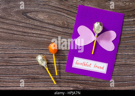 Das Kind macht für eine Grußkarte mit Herz und Schmetterling-Lollipop-Geburtstag. Kinder Kunst-Projekt, ein Handwerk für Kinder. Basteln für Kinder. Stockfoto