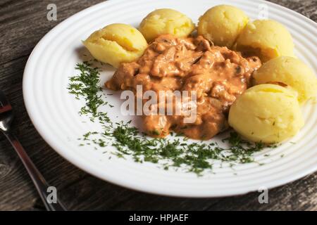 Russische Küche. Boeuf Stroganoff mit Kartoffelpüree auf rustikalen Holztisch Stockfoto