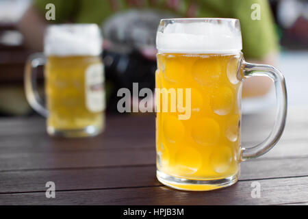 Craft gezapftes Glas. Helles Bier in einer Kneipe-Tabelle. Mann im Hintergrund zu trinken. Geringe Schärfentiefe Stockfoto