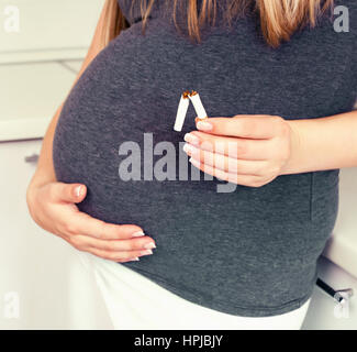 Schwangere Frau versucht, Qiut Rauchen und Zigaretten zu brechen Stockfoto