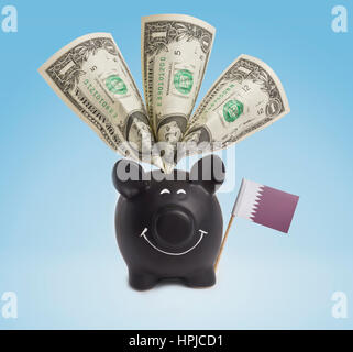 Ein-Dollar-Banknote in ein lächelndes Sparschwein von Katar. (Serie) Stockfoto