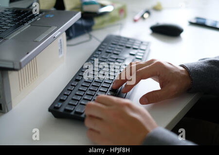 Nahaufnahme von den Händen eines Mannes auf einer schwarzen Tastatur tippen Stockfoto