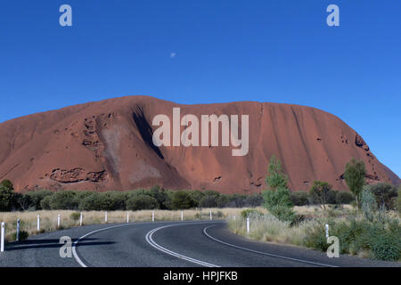 Ayers Rock kontrastiert durch die strahlend blauen Himmel mit Mond sichtbar. Stockfoto