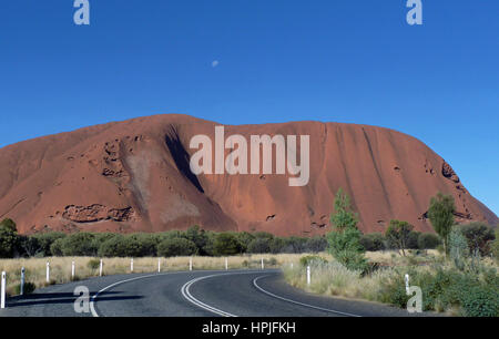 Ayers Rock kontrastiert durch die strahlend blauen Himmel mit Mond sichtbar. Stockfoto