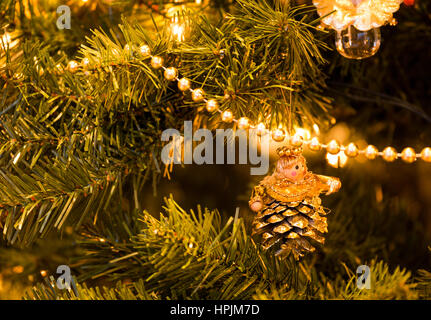 Nahaufnahme von Engel Deko aus Pine Cone auf Christbaum mit Lichtern und String mit Perlen Stockfoto