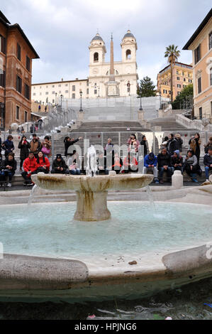 Rom, Italien - 14. März 2016: Touristen, die die Piazza di Spagna (spanischer Platz), die spanische Treppe und die Fontana della Barcaccia in Rom Stockfoto