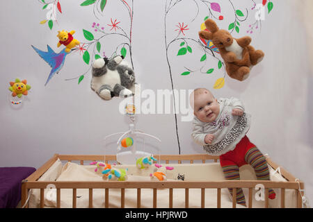 Baby Mädchen sitzen fliegen auf dem Bett auf weißem Hintergrund Stockfoto