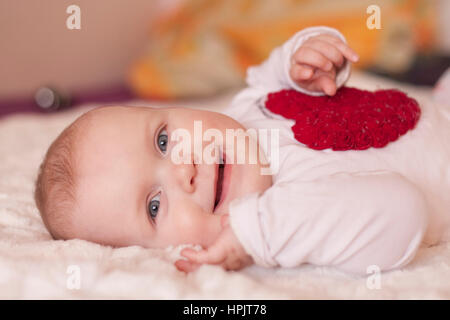 Baby Mädchen sitzen fliegen auf dem Bett auf weißem Hintergrund Stockfoto