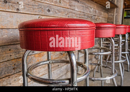 Eine Reihe von vier glänzenden roten Vinyl Hocker an einem Mittagessen im freien-Theke in Austin, Texas Stockfoto