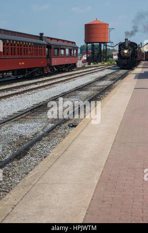 Zwei alte Eisenbahnen, vorbei an einem hellen roten Wasserturm bei Strasburg Railroad in der Nähe von Lancaster, Pennsylvania Stockfoto