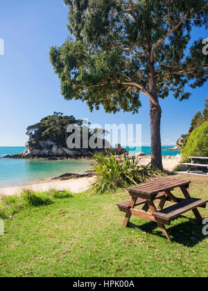 Kaiteriteri, Tasman, Neuseeland. Picknick-Tisch auf dem Rasen hinter dem Strand am kleinen Kaiteriteri einladen. Stockfoto