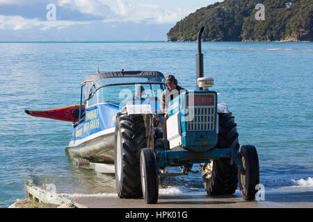 Marahau, Tasman, Neuseeland. Traktor Abschleppen typische Abel Tasman National Park-Wasser-Taxi, Kajak geschnallt, das Boot ist streng. Stockfoto