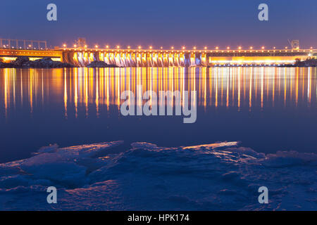 Abends Blick auf DneproGES Damm am Dnjepr im Winter mit Spiegelung im eisigen Wasser, Zaporozhye, Ukraine Stockfoto