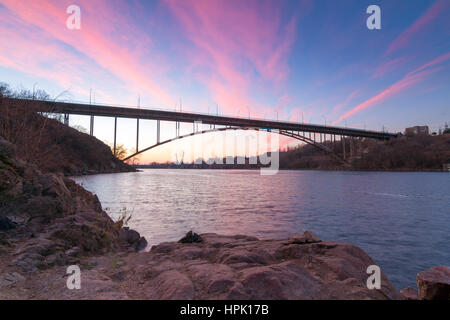 Gewölbte Stahlbrücke auf alten Dnjepr mit hellen Wolken Abendhimmel im Wasser und antiken Granit Felsen, Insel Chortyzja, Zaporozhye, Ukr Stockfoto