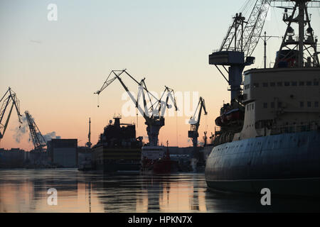 Seehafen-Silhouetten von Schiffen und Portalkräne im Abendhimmel Stockfoto
