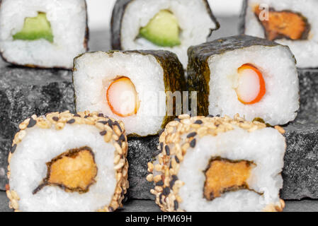 verschiedene Sushi-Gerichte auf dunklen grauen Steinoberfläche Stockfoto