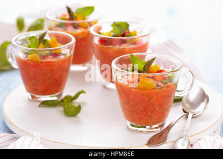 Kalte Tomatensuppe (Gazpacho) in kleinen Tassen auf Holz Schneidebrett. Stockfoto