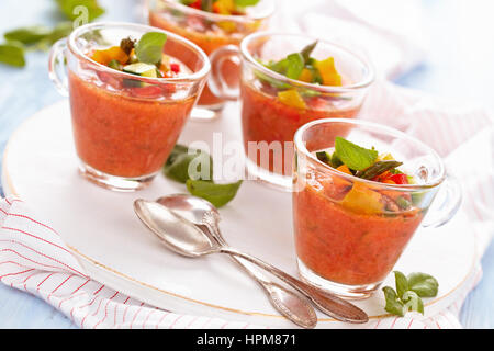 Kalte Tomatensuppe (Gazpacho) in kleinen Tassen auf Holz Schneidebrett. Stockfoto