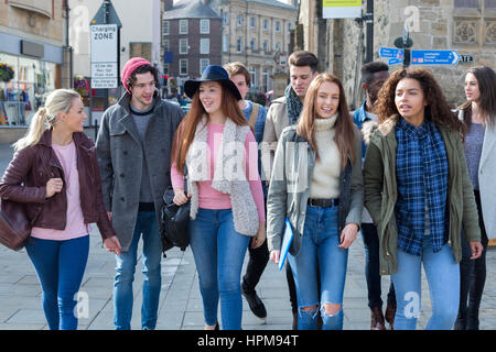 Eine glückliche Gruppe von Jugendlichen Studenten Lächeln, als sie ihren Weg zu ihren Klassen für Universität machen. Sie tragen ihre Taschen, Bücher und Technologie Witz Stockfoto