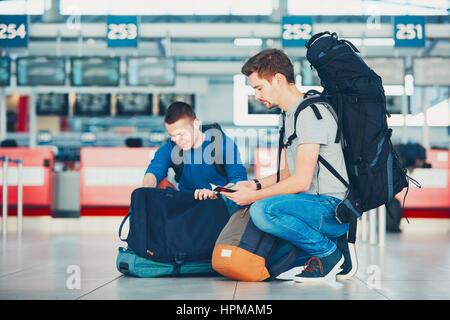 Zwei Freunde, Reisen mit dem Flugzeug. Reisende, die Vorbereitung einen Reisepass und ein Flugticket am Flughafen einchecken. Stockfoto