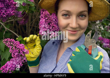 Schöne junge Frau arbeitet im Garten mit einer Gartenschere. / Farbeffekte und benutzerdefinierte Ewhite Gleichgewicht auf diesem Bild verwendet. Stockfoto