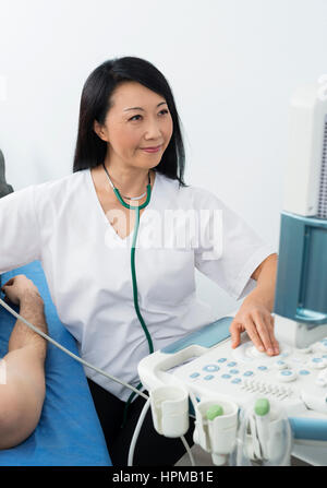 Lächelnd operative Ultraschallgerät Ärztin bei der Untersuchung männlichen Patient im Krankenhaus Stockfoto