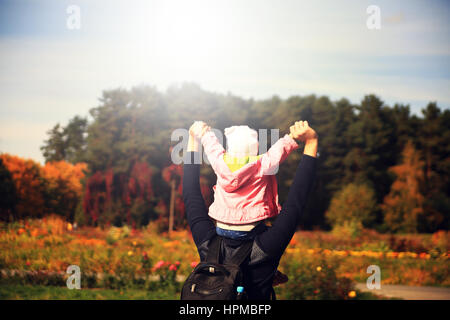 Glückliche kleine Mädchen sitzen auf Vater Hals auf einem sonnigen Tag im freien Stockfoto