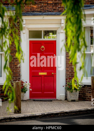 Rot Front Tür Haus gesehen durch Äste der Trauerweide in Easingwold, Yorkshire, Großbritannien. Stockfoto