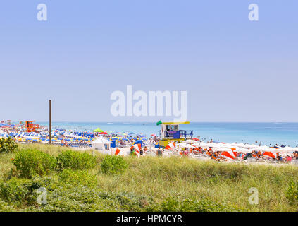 MIami Beach, USA - 9. Mai 2015: Abschnitt des Strandes mit Rettungsposten und viele bunte Sonnenschirme und Liegestühle in den vorderen Dünen mit Stockfoto