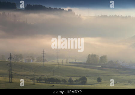 Elektrische Hochspannungsleitungen auf misty Mountain Hügeln Stockfoto