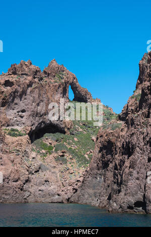 Vulkanische rote Klippen ergeben sich aus dem blauen Meer im Naturpark Scandola. Stockfoto