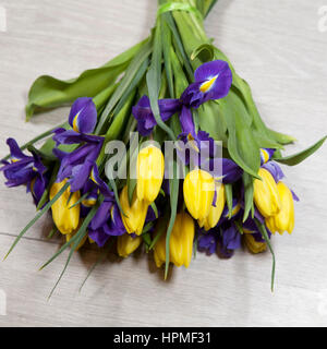 Bouquet von gelben Tulpen und blauen Schwertlilien liegend auf dem Holzboden Stockfoto