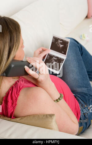 Schwangere Frau mit Blick auf eine Ultraschall-Foto ihres Babys Stockfoto