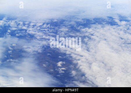 Zeigen Sie auf der Erde durch weiße Wolken aus Flugzeug an Stockfoto