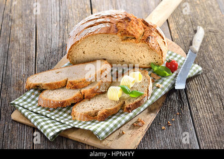 Frisch gebackenes Brot mit Butter-Brötchen serviert auf einem alten Holzbrett Backen Steinofen Stockfoto