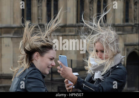 Frauen versuchen, ein "Selbstporträt" auf Westminster Bridge, London, zu nehmen, da Flüge abgesagt wurden und Pendler, dass sie Verzögerungen konfrontiert gewarnt wurden, nachdem Sturm Doris fast 90 km/h auf dem Weg zum Teig Großbritannien erreicht. Stockfoto