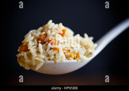 Pilaw gekocht in einem großen weißen Löffel auf schwarzem Hintergrund Stockfoto