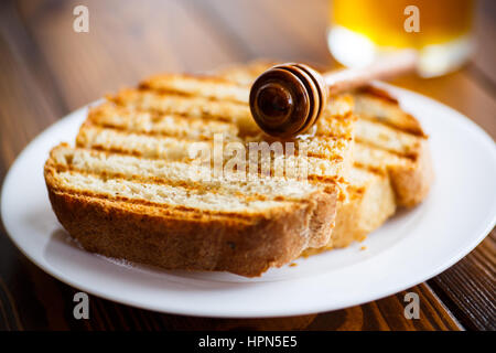 Gebratener Toast mit Honig auf einem Holztisch Stockfoto