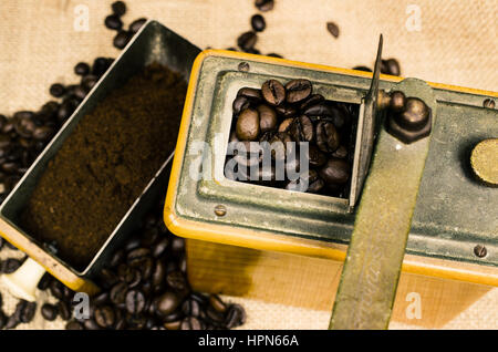 Espresso-Bohnen in eine alte Kaffeemühle auf einem rustikalen Hintergrund, Vintage Farbe getönt Stockfoto