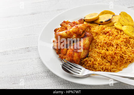 Jollof Reis mit Huhn und gebratenen Kochbananen, westafrikanische Küche Stockfoto