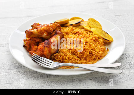 Jollof Reis mit Huhn und gebratenen Kochbananen, westafrikanische Küche Stockfoto