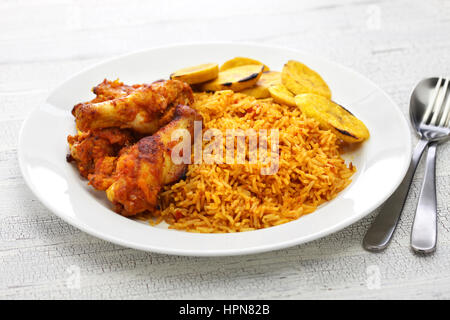 Jollof Reis mit Huhn und gebratenen Kochbananen, westafrikanische Küche Stockfoto
